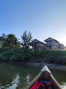 a person in a kayak on a river with houses at Chivarin Resorts in Malvan