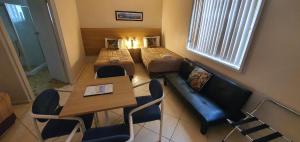 ネルソン・ベイにあるCentral Motel Nelson Bayのベッド、テーブル、椅子が備わる小さな客室です。