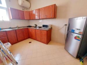 a kitchen with wooden cabinets and a stainless steel refrigerator at DO ALL BY WALKING DISTANCE IN ALAIN in Al Ain