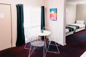 a room with a table and chairs and a bed at Motel Poinsettia in Port Augusta