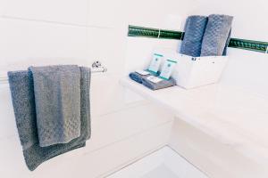 a white bathroom with blue towels on a shelf at Motel Poinsettia in Port Augusta