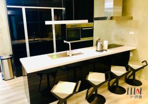 a kitchen with a white counter and stools at Three Adds One Homestay in Luodong