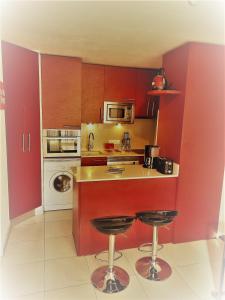 a kitchen with red cabinets and two bar stools at Hikoa Hendaia-Hendaye plage in Hendaye