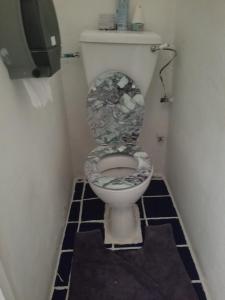 a bathroom with a toilet with a tile floor at Rio Guesthouses in Christ Church