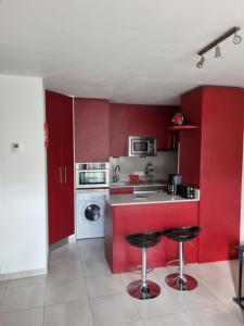 a kitchen with red cabinets and a washing machine at Hikoa Hendaia-Hendaye plage in Hendaye