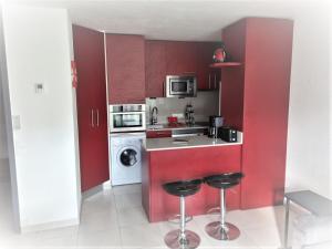 a kitchen with red cabinets and two bar stools at Hikoa Hendaia-Hendaye plage in Hendaye