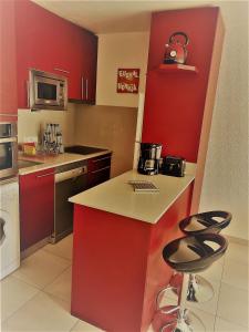 a kitchen with red cabinets and two bar stools at Hikoa Hendaia-Hendaye plage in Hendaye