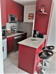 a kitchen with red cabinets and a counter with stools at Hikoa Hendaia-Hendaye plage in Hendaye