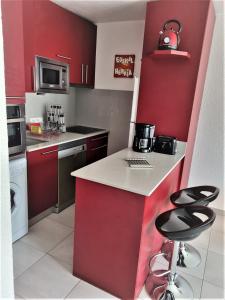 a kitchen with red cabinets and a counter with stools at Hikoa Hendaia-Hendaye plage in Hendaye +29 photos