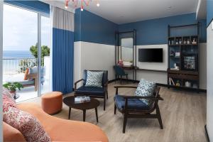 Avani Chaweng Samui Hotel & Beach Club في شاطئ تشاوينغ: غرفة معيشة بها أريكة وكراسي وتلفزيون