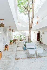 a courtyard with a tree and tables and chairs at Ahava Hotel in Playa del Carmen