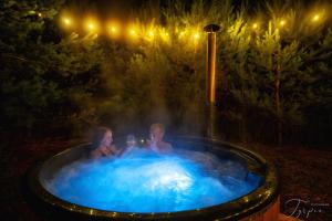 two people sitting in a hot tub at night at Dziupla House in Czarna