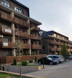 um prédio de apartamentos com carros estacionados em frente em Kalman Iskra em Zlatibor