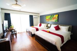 a hotel room with two beds and a television at Paradiso Resort & Spa in Saipan