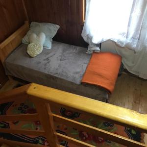 a small bed in a room with a wooden floor at Cabana Trei Brazi Dambovita in Bezdead