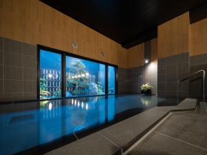 a swimming pool in a building with a large window at Hotel Route-Inn Saku Minami Inter in Saku