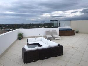 a patio with a couch and chairs on a balcony at Grand Mercure Allegra Hervey Bay in Hervey Bay