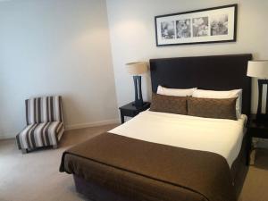 a bedroom with a large bed and a chair at Grand Mercure Allegra Hervey Bay in Hervey Bay