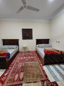 two beds in a room with a rug at Green House in Al Manshīyah