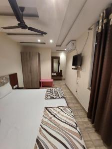 a room with two beds and a flat screen tv at HOTEL SATYAM PALACE in Deoghar