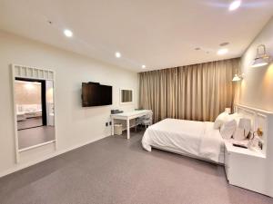 um quarto de hotel com uma cama, uma secretária e uma televisão em Embledon Hotel em Ansan