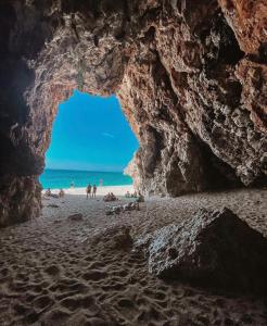 a cave on a beach with people in the water at Old Town Hotel Dhermi in Dhërmi
