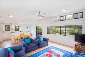 a living room with two blue chairs and a tv at Beach Retreat in Mollymook