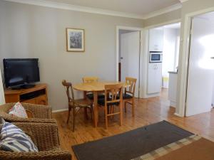 a living room with a table and chairs and a television at Donlan's Beach Cottage in Mollymook