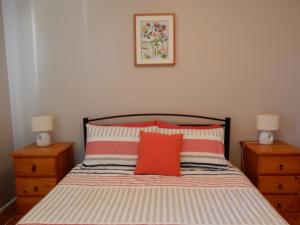a bedroom with a bed with two dressers and two lamps at Donlan's Beach Cottage in Mollymook