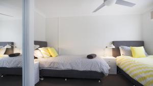 a bedroom with two beds and a mirror at Mariners 2 in Mollymook
