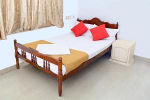 um quarto com uma cama com almofadas vermelhas e brancas em Zion Lodge em Cochin