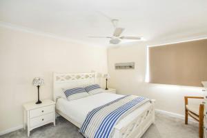 a white bedroom with a bed and a ceiling fan at Summer Days in Mollymook