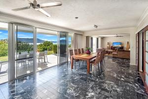 a dining room with a table and a living room at 3 Bedroom Poinciana Lodge in Hamilton Island