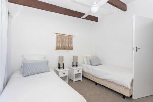 two beds in a bedroom with white walls and a ceiling at Tee to Sea in Mollymook