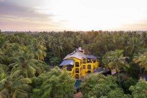 uma casa amarela no meio de uma floresta de árvores em Whoopers Boutique Hotel, Anjuna em Anjuna