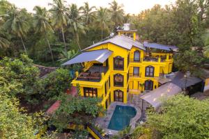 an overhead view of a yellow house with trees at Whoopers Boutique Hotel, Anjuna in Anjuna