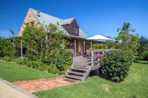 a house with a wooden staircase and an umbrella at Stone Cottage in Milton