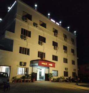 - un grand bâtiment blanc avec des fenêtres la nuit dans l'établissement Hotel Joshi, à Siddharthanagar