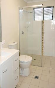 a bathroom with a toilet and a glass shower at Monterey Apartments Moranbah in Moranbah