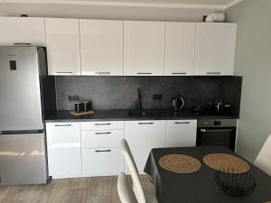 una cocina con armarios blancos y una mesa. en Apartament Widok&Sky Piechowice/Szklarska Poręba, en Piechowice