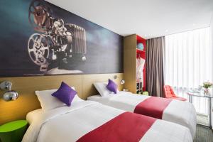 首尔ibis Styles Ambassador Seoul Myeong-dong的一间有两张床的酒店房间，墙上挂着一幅画