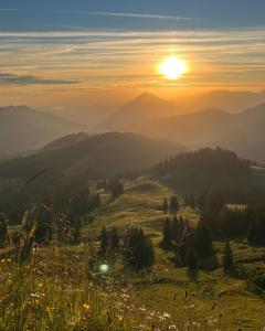 einen Sonnenuntergang auf einem Hügel mit der Sonne in der Ferne in der Unterkunft Gipfel Stuben in Blaichach