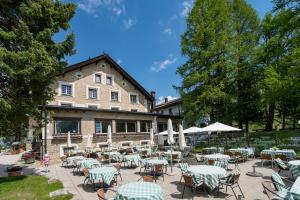 a group of tables and chairs in front of a building at Hotel Sonne Fex Alpine Hideaway in Sils Maria