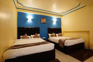 2 camas en una habitación con paredes azules en Hotel White Lotus Gangtok en Gangtok