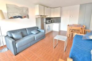 a living room with a couch and a kitchen at CONFORTABLE APPARTEMENT GRANDE TERRASSE PISCINE PARKING CLIM in Cap d'Agde