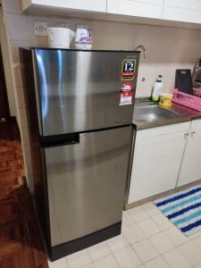 um frigorífico de aço inoxidável numa cozinha ao lado de um lavatório em Tanjung tuan regency private PD em Porto Dickson