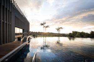 een zwembad naast een gebouw met palmbomen bij ADLER Spa Resort SICILIA in Siculiana