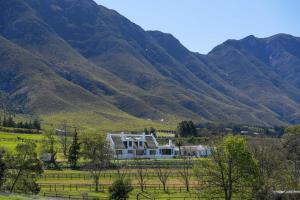 a house in a field with mountains in the background at Hemel 'N Aarde Stud in Hermanus