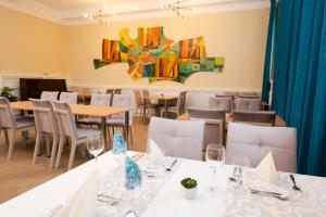 a dining room with tables and chairs and a painting on the wall at Hotel DSZSU in Trenčianske Teplice