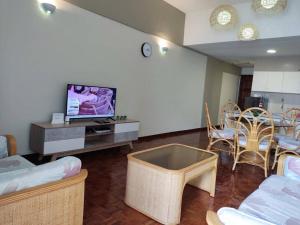 uma sala de estar com televisão e algumas cadeiras em Tanjung tuan regency private PD em Porto Dickson